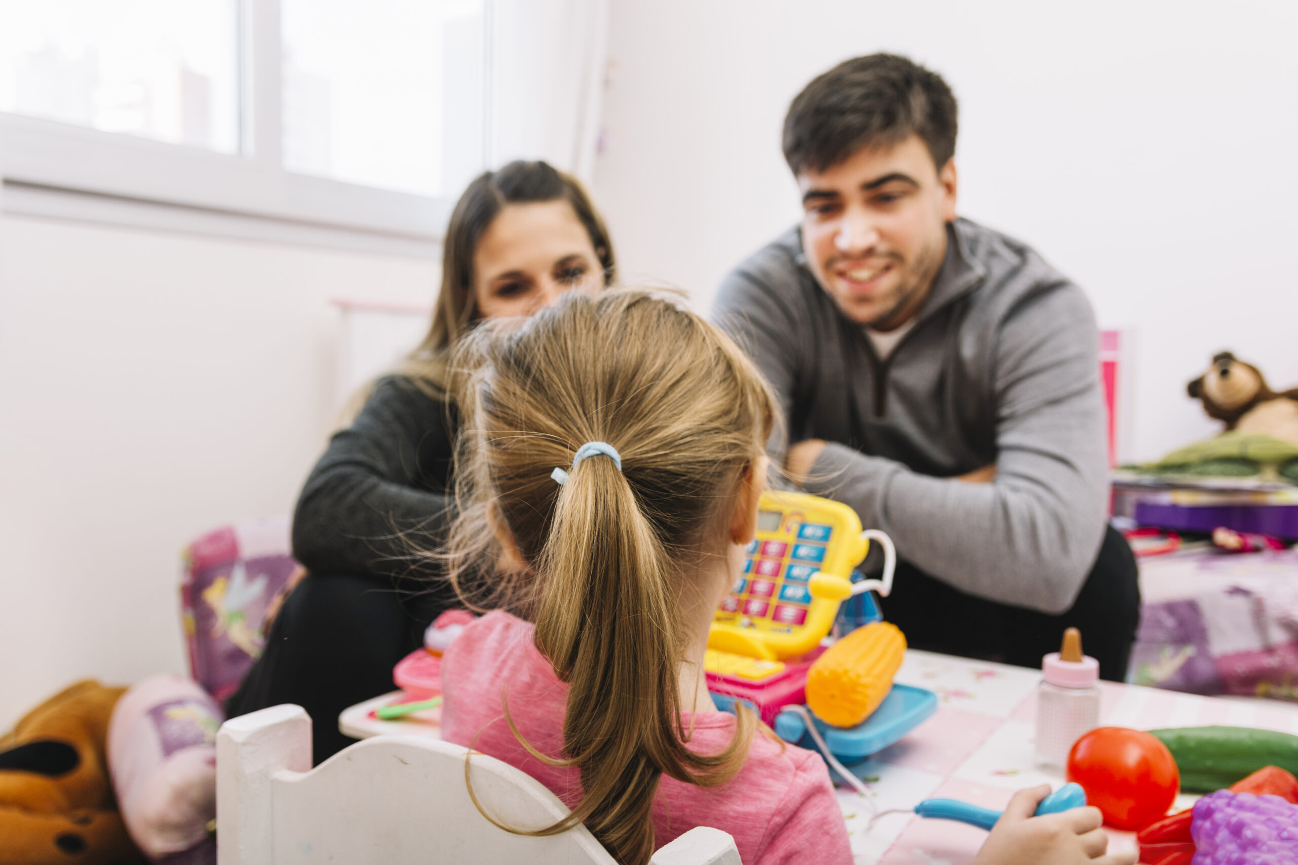 parents-looking-their-daughter-playing-with-toys